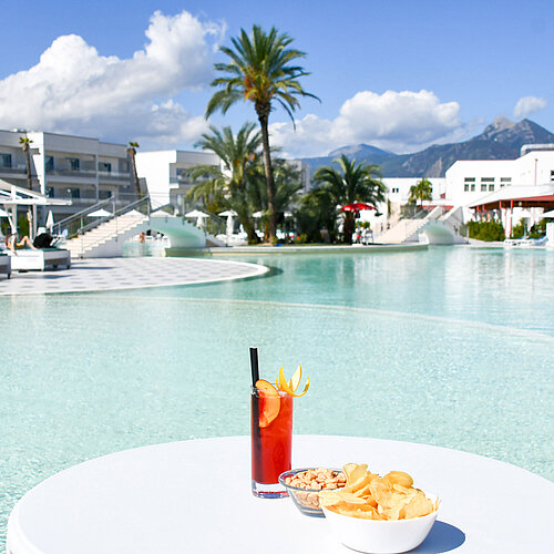 Snacks and a cocktail by the lagoon pool at Maritim Resort Calabria. Perfect retreat with mountain views.