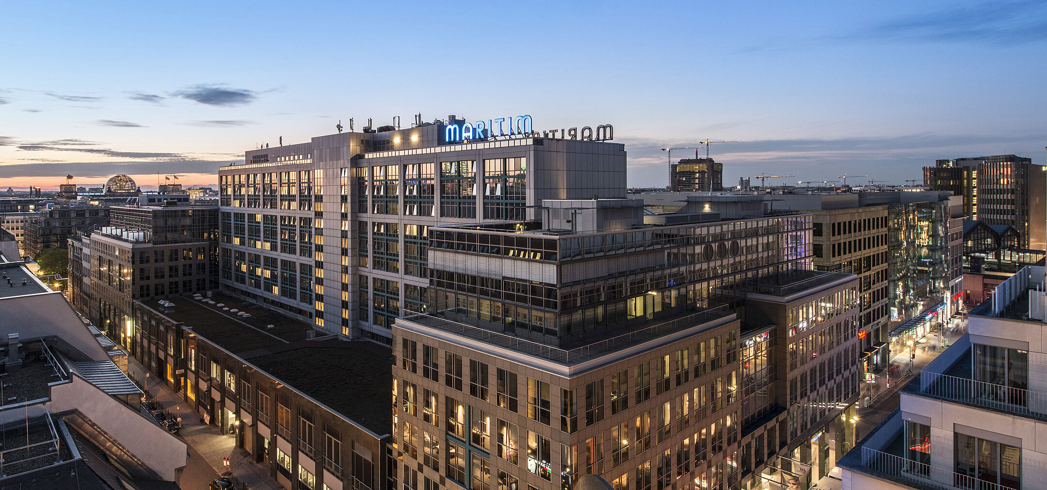 View of Maritim proArte Hotel Berlin at dusk, surrounded by modern buildings in the heart of Berlin.