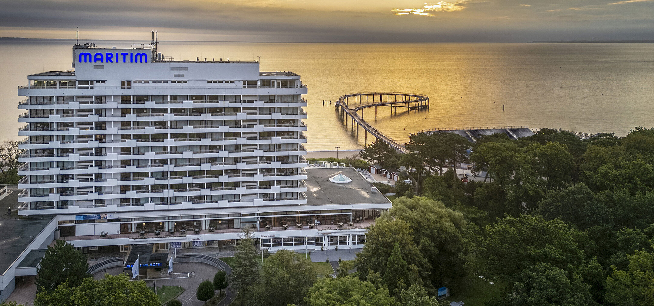 Maritim Seehotel Timmendorfer Strand at sunrise with a pier and sea view.