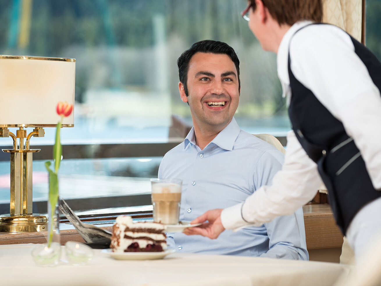 Schwarzwälderkirschtorte Lächelnder Gast im Restaurant des Maritim Hotel Titisee beim Servieren von Latte Macchiato und Torte