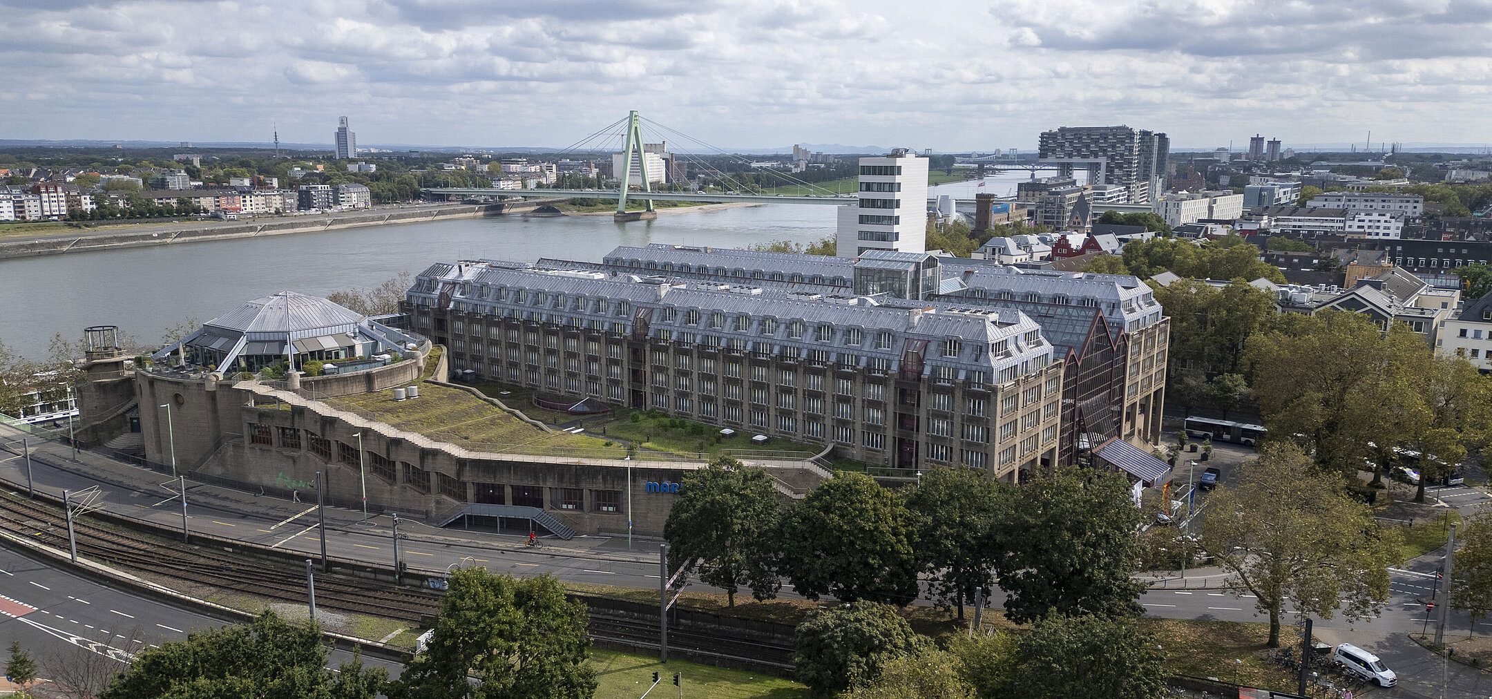 Aerial view of the Maritim Hotel Cologne, featuring the Rhine River, Severins Bridge, and surrounding buildings.